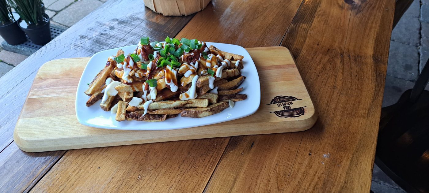 Poutine garnie d'oignons verts sur une planche de bois